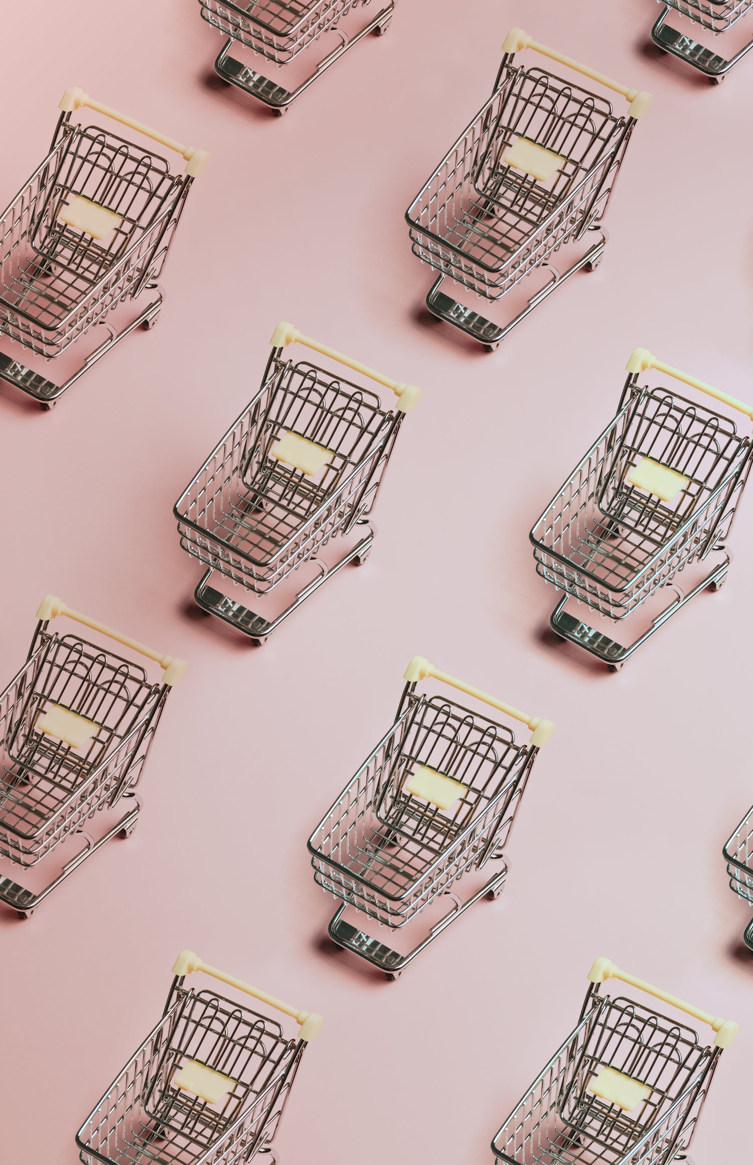 A pattern of silver shopping carts on a pink background